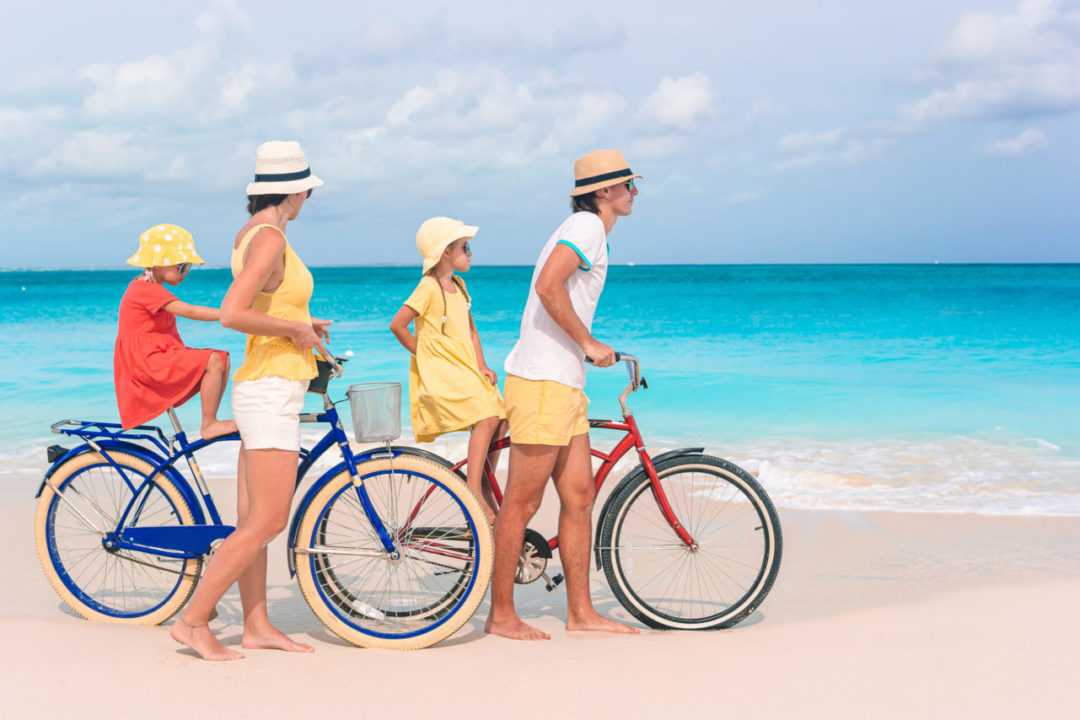 Family riding bicycles on tropical beach
